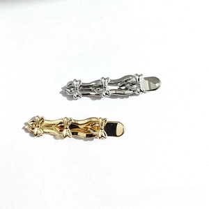 Detail of silver and gold wave-shaped hairpins with embossed butterfly accents