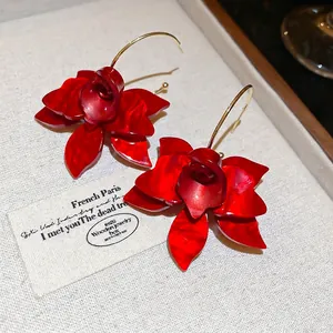 French vintage red resin flower drop earrings with gold hooks on beige texture