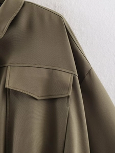 Detail of olive green bomber jacket featuring a smooth fabric texture and a flap pocket