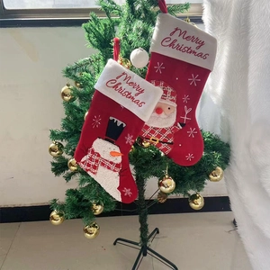 Close-up of red felt Christmas stockings with Snowman and Santa embroidery on tree