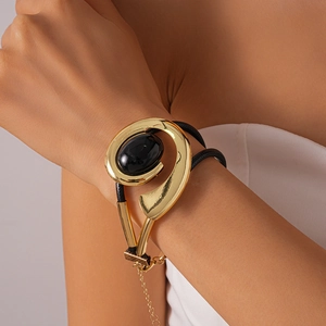 Détail d'un bracelet géométrique vintage en métal doré avec pierre ovale noire et corde