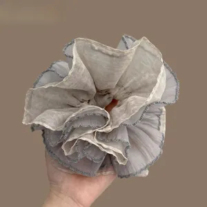 Macro shot of large light grey layered chiffon scrunchie with dark grey lace trim