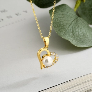 Elegant gold necklace with a heart pendant featuring diamonds and a white pearl