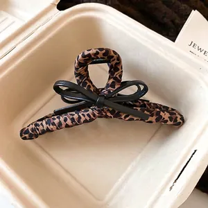 Leopard print fabric hair claw clip with black faux leather bow on paper pulp tray