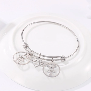 Adjustable stainless steel bangle with boy, heart, and girl charms on a ceramic tray