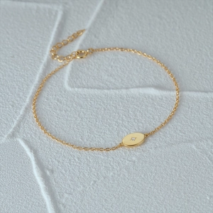 Detail showing gold oval charm with starburst setting and adjustable lobster clasp chain