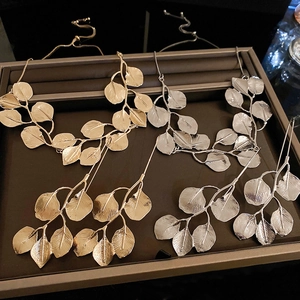 Detailed flat lay of metal leaf necklace and earring sets in gold and silver finishes