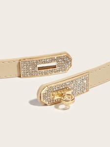 Macro shot of gold-tone Kelly buckle with rhinestones on a beige leather belt