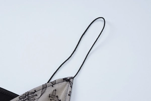 Close-up of black lace patterns with beige lining and thin straps on the dress