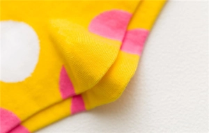 Close-up of bright yellow cotton socks with pink and white polka dots and knit texture