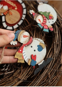 Handheld view of a hand-painted wooden snowman ornament for rustic Christmas tree decor