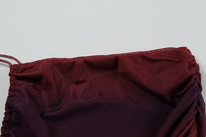 Détail du tissu en maille dégradé rouge-violet avec texture froncée à cordon