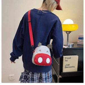 Close-up of cute cartoon canvas crossbody bag with red straps and animal ear details