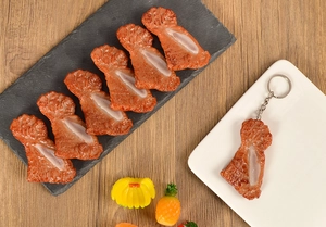 Close-up of realistic faux lamb chop keychain with textured bone on a black stone plate