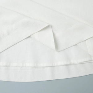Detailed view of white sleeveless top hem with woven texture and neat stitching
