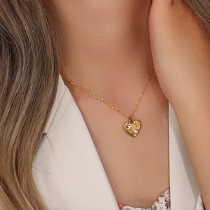 Close-up of golden heart pendant necklace with sparkling stones worn by a model