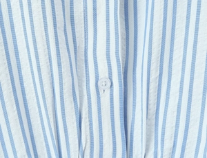 Detail of blue and white seersucker fabric with vertical stripes and a clear button