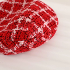 Gros plan sur le tissu en tweed rouge d'un béret avec texture tissée pour enfant et femme