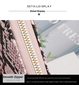Detailed macro view of the smooth gold-plated metal zipper on pink snakeskin wallet