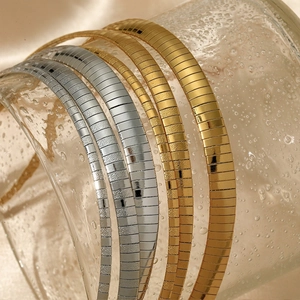Chaînes de serpent plates minimalistes en acier inoxydable doré et argenté sur verre mouillé