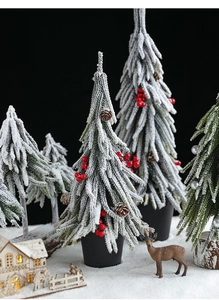 Miniature snow-covered Christmas trees with red berries and pine cones for desktop decor