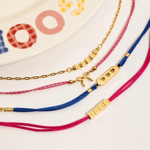 Détail de cordes tressées rouge rose et de bracelets d'amitié LOVE en acier inoxydable doré 18K