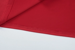 Vue macro de l'ourlet à double couture et détails de finition sur robe en maille rouge