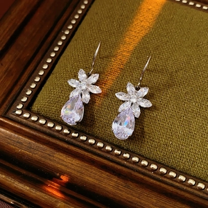 Detailed view of silver zircon flower earrings on vintage green velvet display