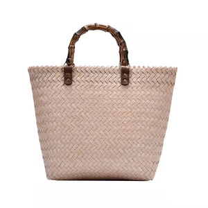 Pink woven straw tote bag with natural bamboo handles and vintage leather details