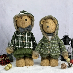 Christmas telescopic plush bears in green knit outfits standing on snow with festive decor