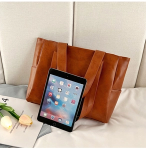 Detailed texture of caramel PU leather tote bag with iPad for size reference