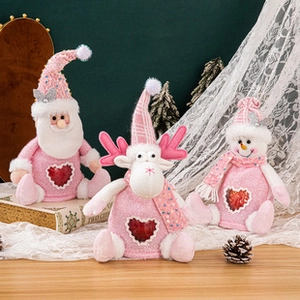 Three pink Christmas plush toys featuring Santa, elk and snowman on a wooden table
