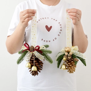 Christmas pine cone ornaments with red velvet ribbons, gold stars, and festive bells