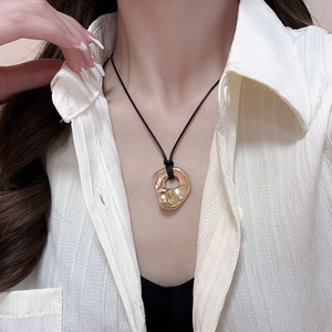 Close-up of gold irregular heart pendant with black cord necklace on a female model