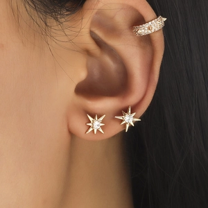 Close-up of gold star stud earrings and pavé zircon ear cuff set worn on ear