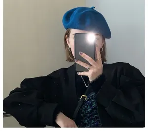 Blue wool beret paired with a black puff-sleeve jacket in a stylish mirror selfie view
