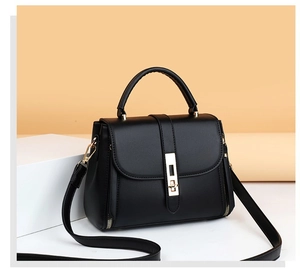 Detail view of black matte leather bag with golden rectangular buckle and metal zipper accents
