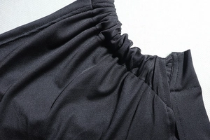 Detail view of the black dress showing elastic pleated fabric and double stitching