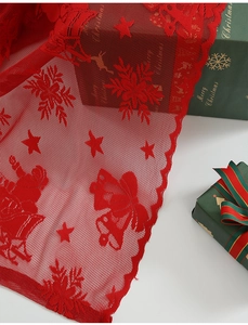 Détail du tissu en dentelle rouge de Noël avec Père Noël, flocons et cloches