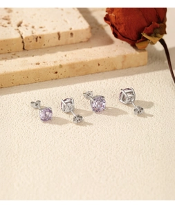 Close-up of four-claw silver stud earrings with round-cut purple zircon on vintage stone