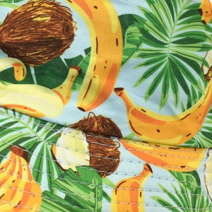 Détail macro du motif banane et palmier sur le tissu en sergé bleu clair du chapeau bob