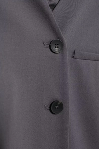 Detailed view of dark grey urban vest fabric with buttons and fine woven texture