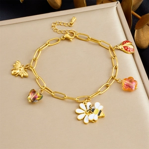 Detail of gold-plated charm bracelet featuring colorful enamel bee and floral pendants