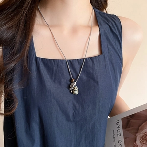 Close-up of a silver tassel necklace featuring a spotted tiger eye stone on a model
