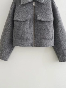 Detail of the grey bouclé texture on a short jacket with metal zipper and collar