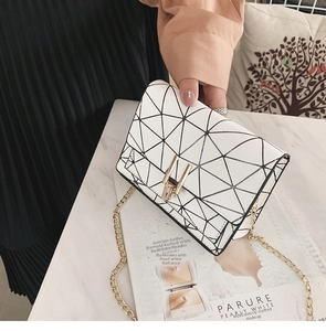 Detail of white mini crossbody bag with black geometric grid pattern and gold chain strap