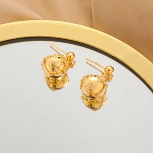 Macro detail of glossy gold sphere earrings with delicate chain texture on mirror surface