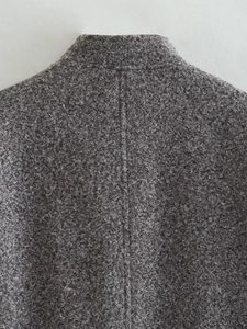 Detailed macro view of the back collar and textured seam on this gray curly wool coat