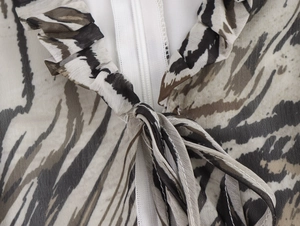 Detail of ruffled stand collar with white zipper and tie on animal print dress