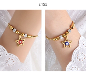 Macro shot of gold bead chain bracelets featuring red and blue evil eye star pendants